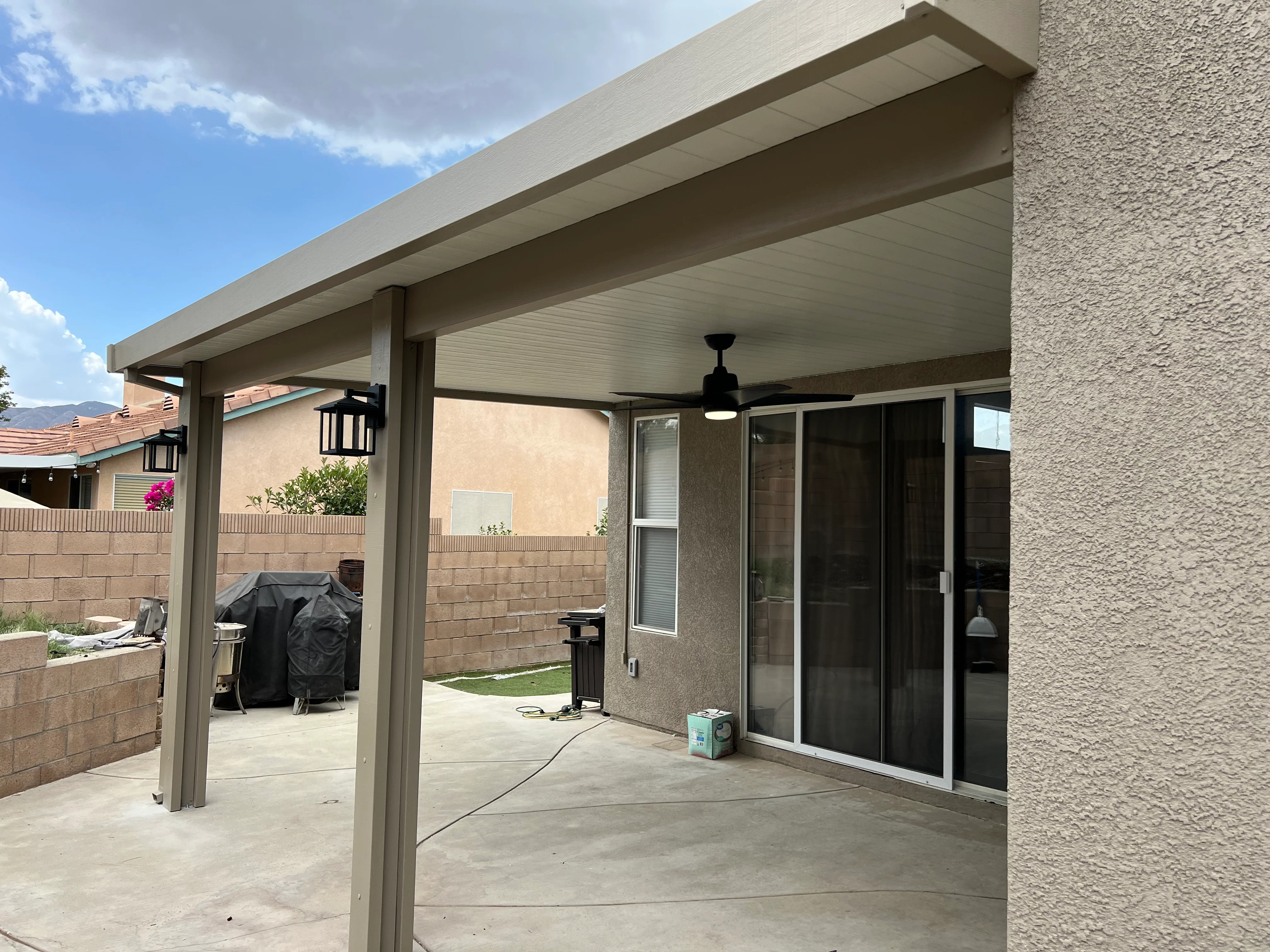 Modern aluminum patio cover with white ceiling and fan over concrete patio