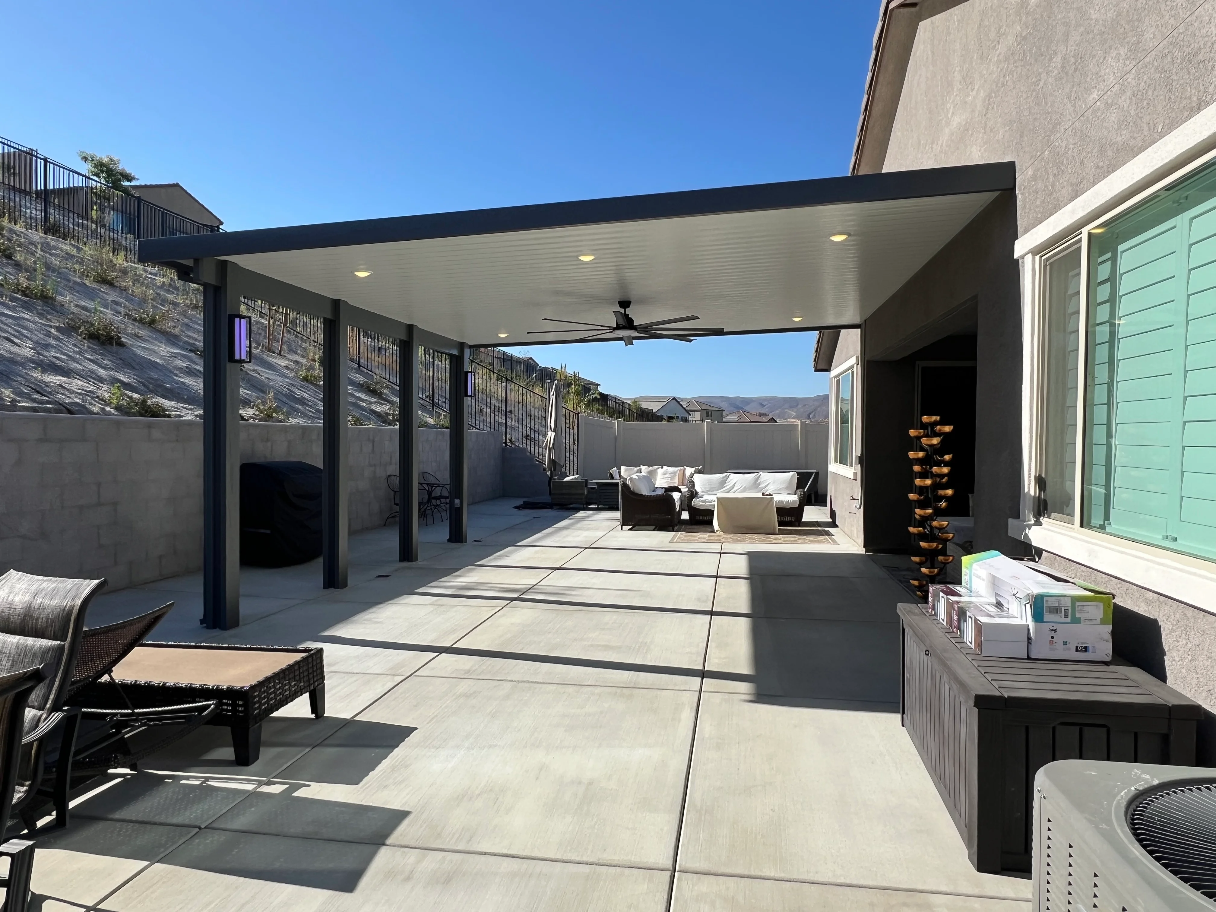 Modern patio cover with white ceiling, black posts, and integrated outdoor furniture