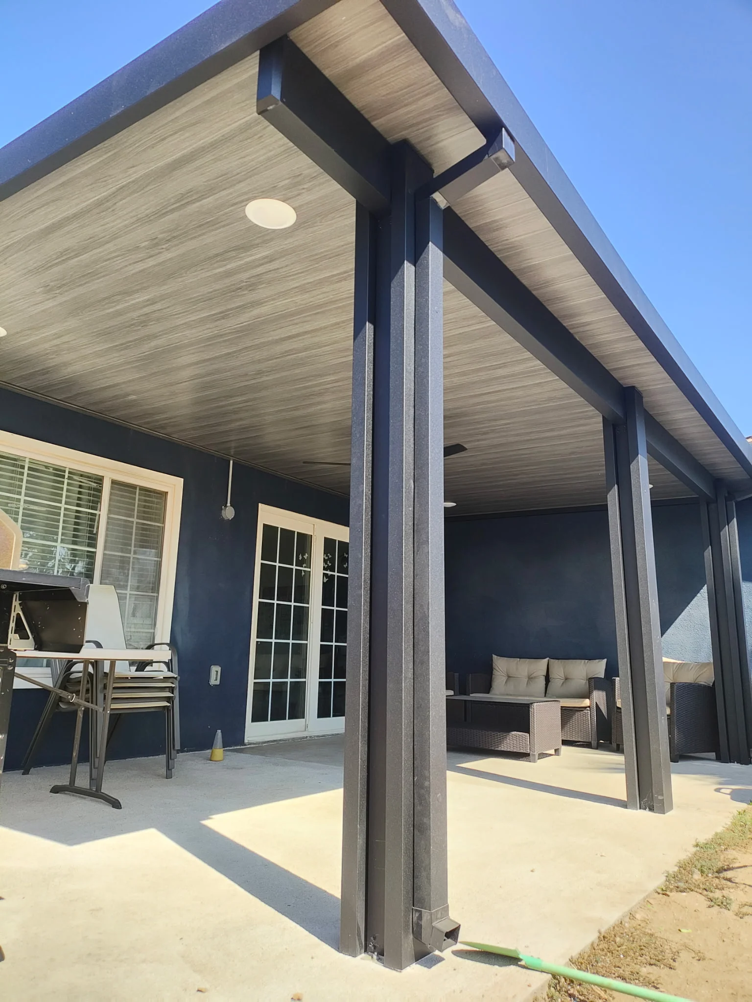 Modern patio cover with composite ceiling, steel columns, and concrete patio area