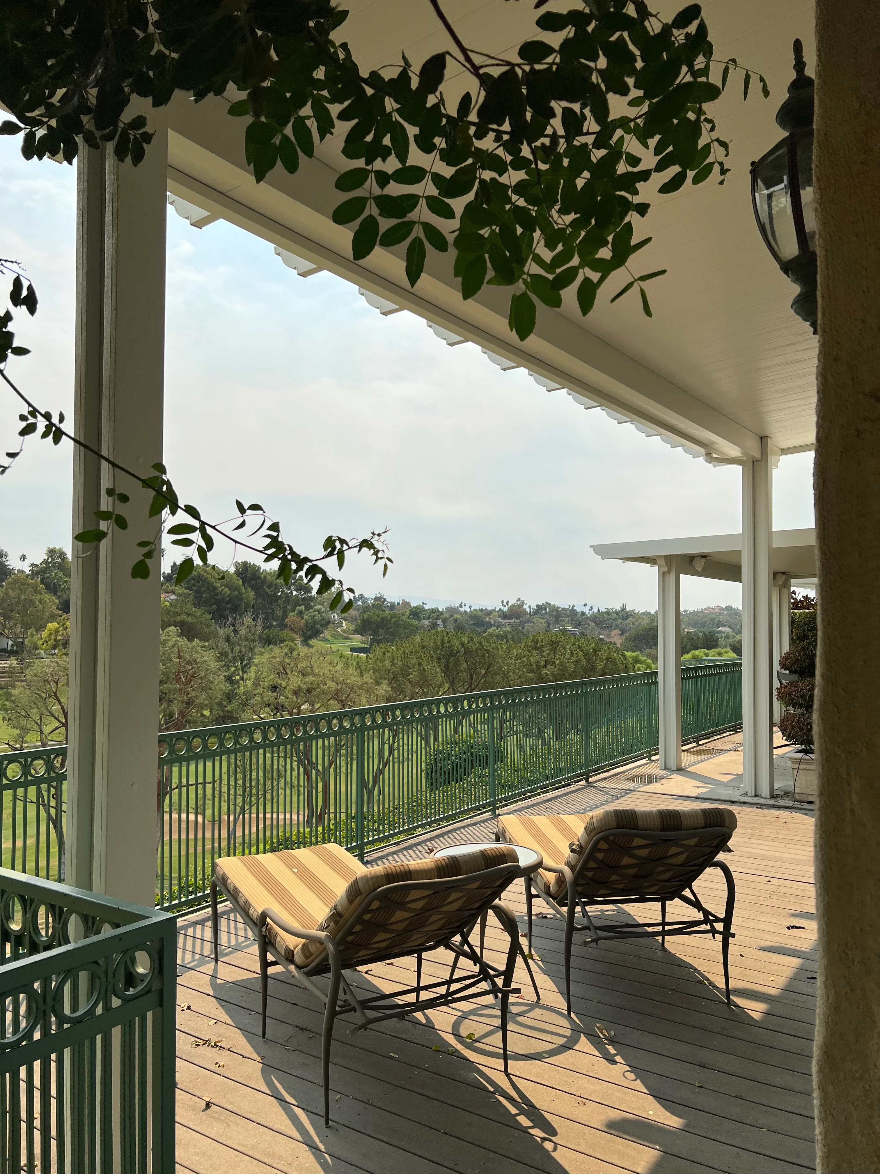 Elevated wooden deck with white pergola, retractable awning, green metal railing, and valley views