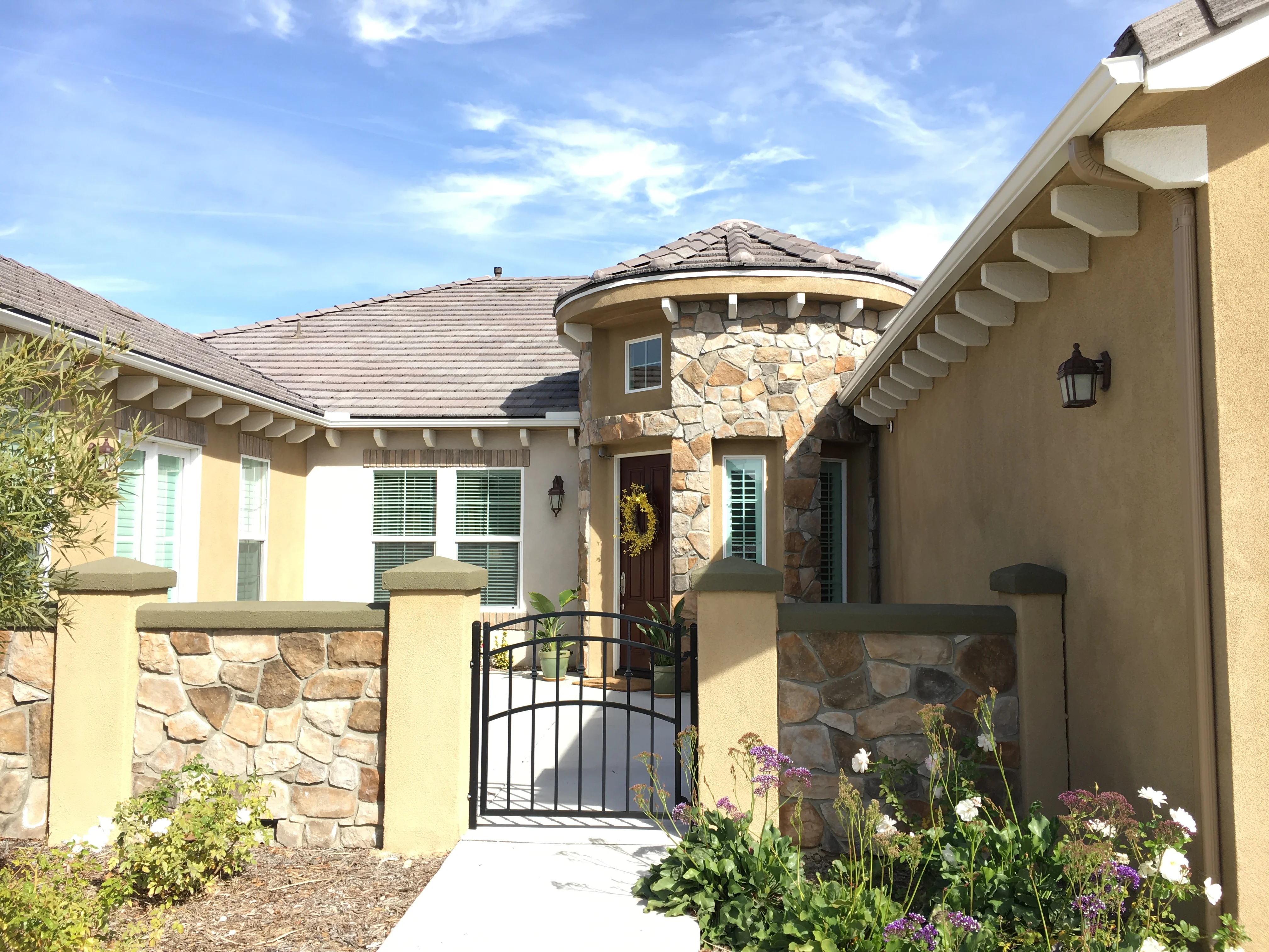 Mediterranean home with new gutters, fascia, and soffit installation along stone and stucco exterior