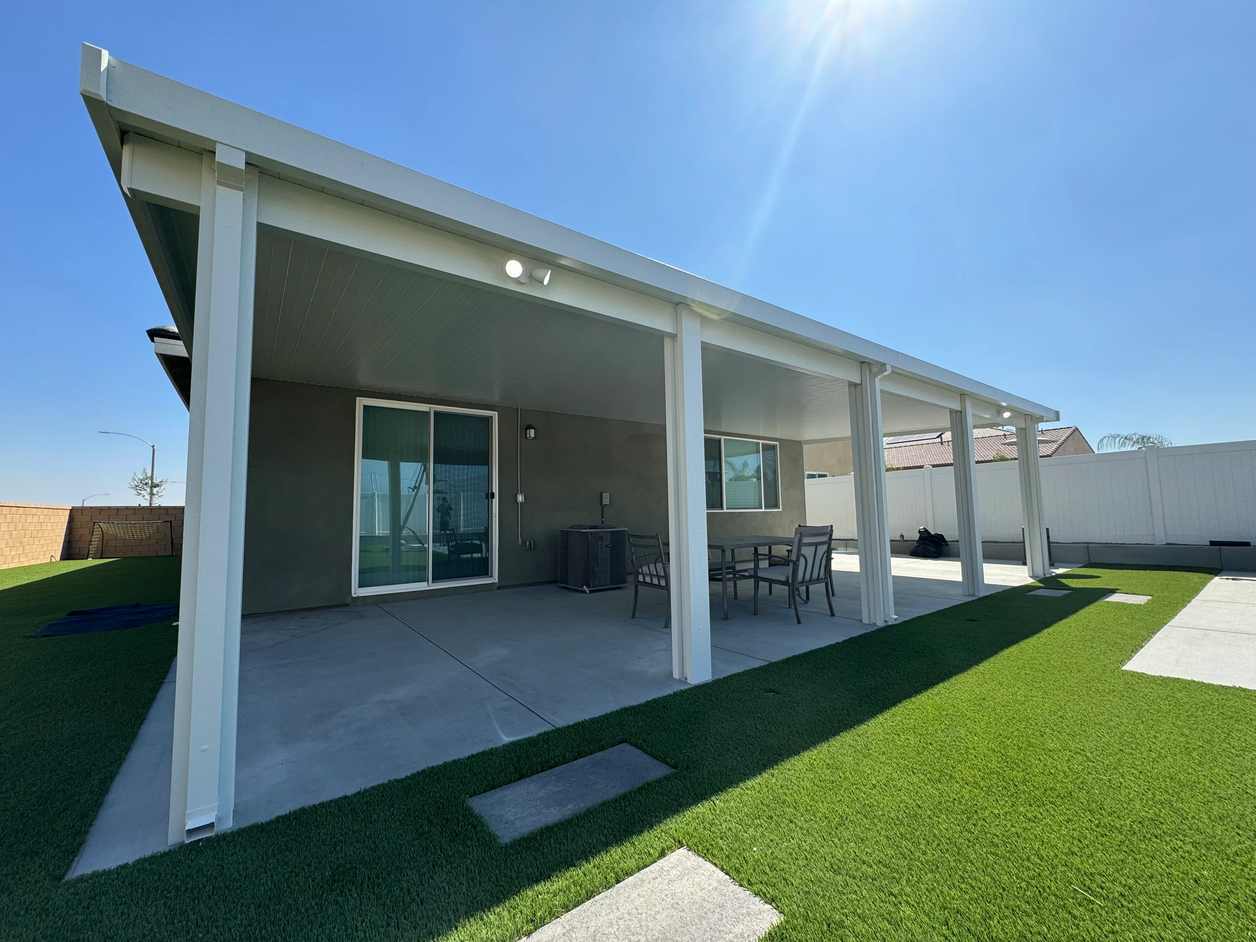 Modern white aluminum patio cover with concrete pad and outdoor dining area