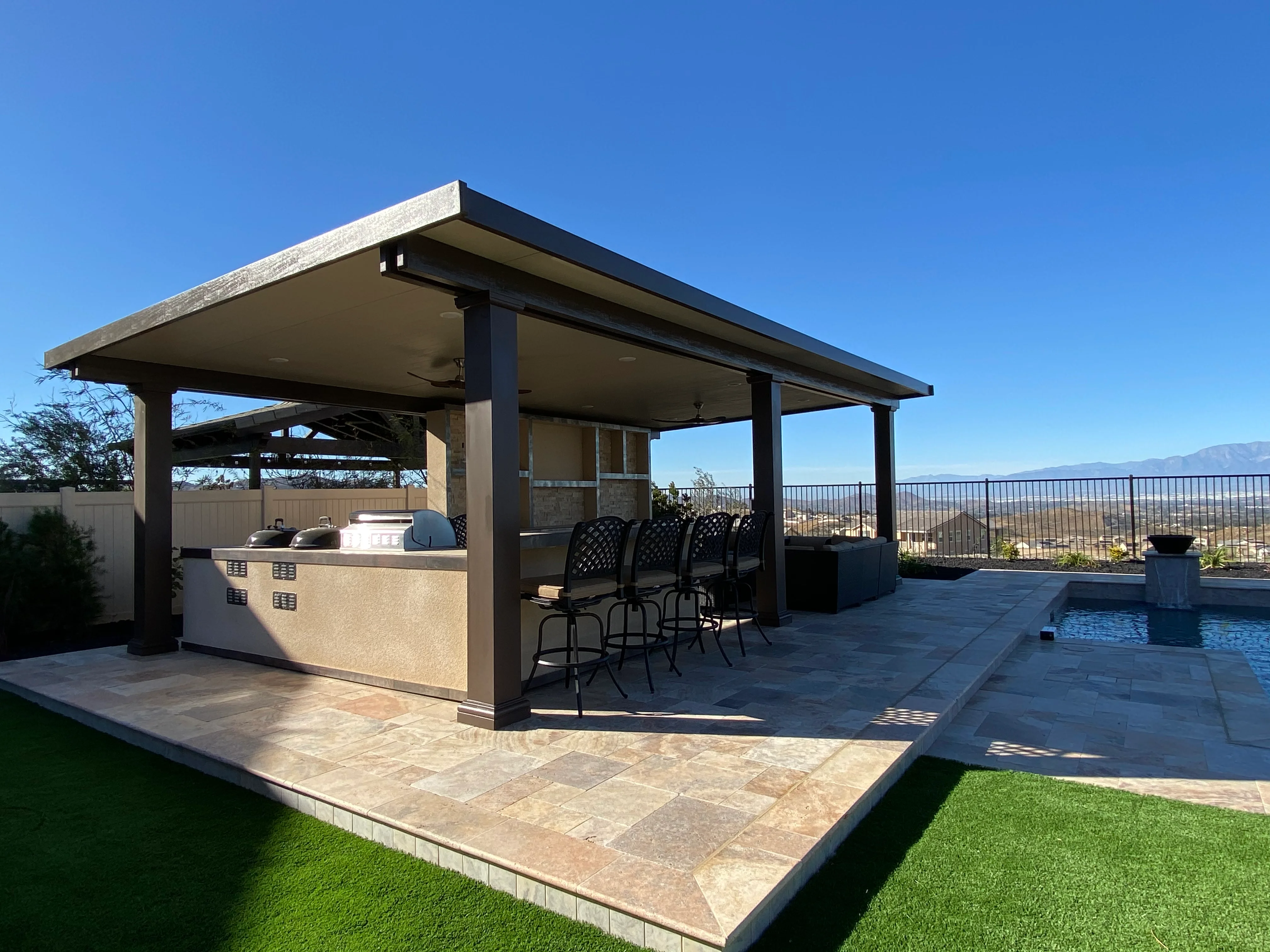 Modern patio with pergola, outdoor kitchen, and pool overlooking Riverside valley