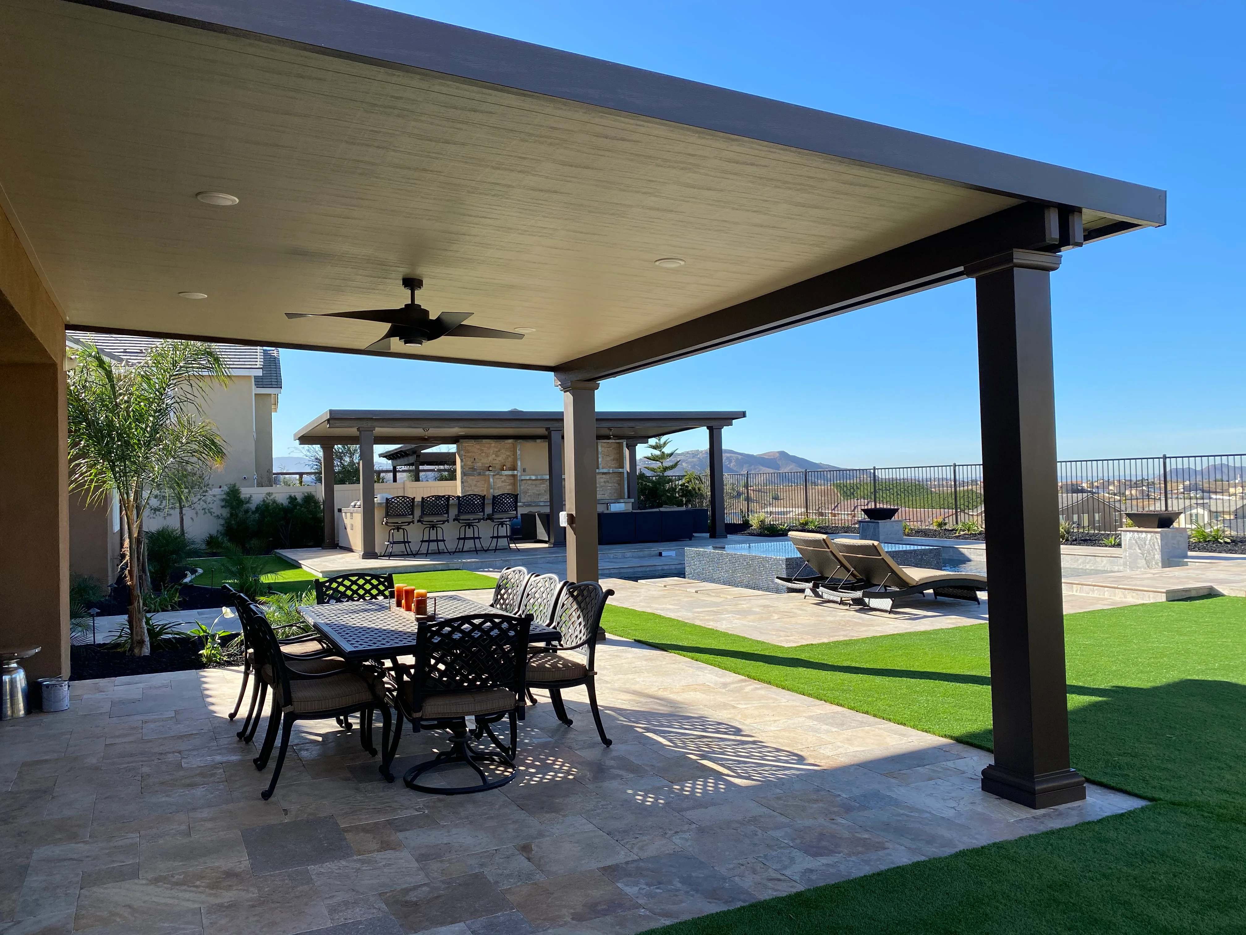 Modern patio with black pergola, dining furniture, pool, and hillside views